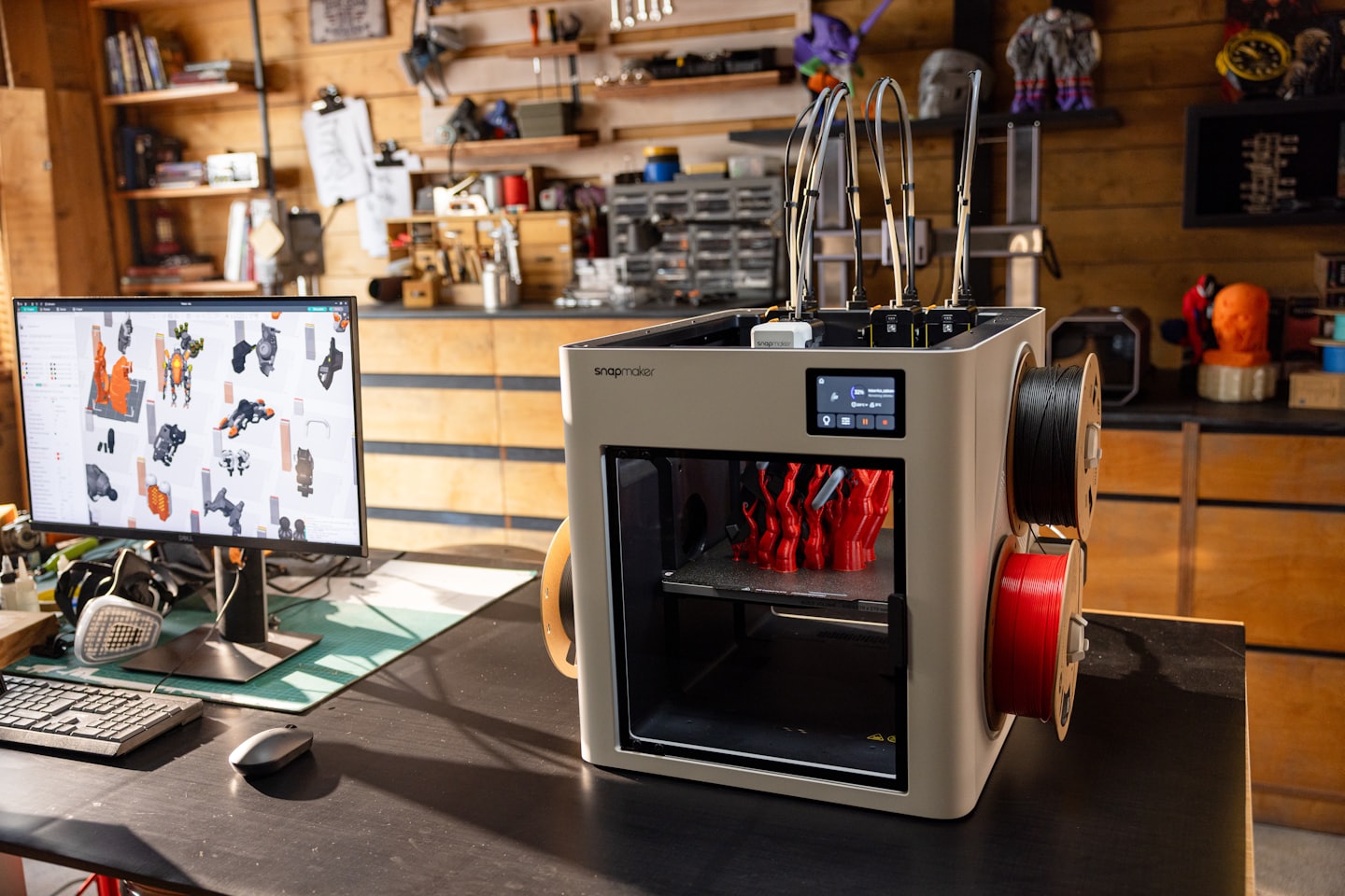 3D printer creating a red object on a desk.