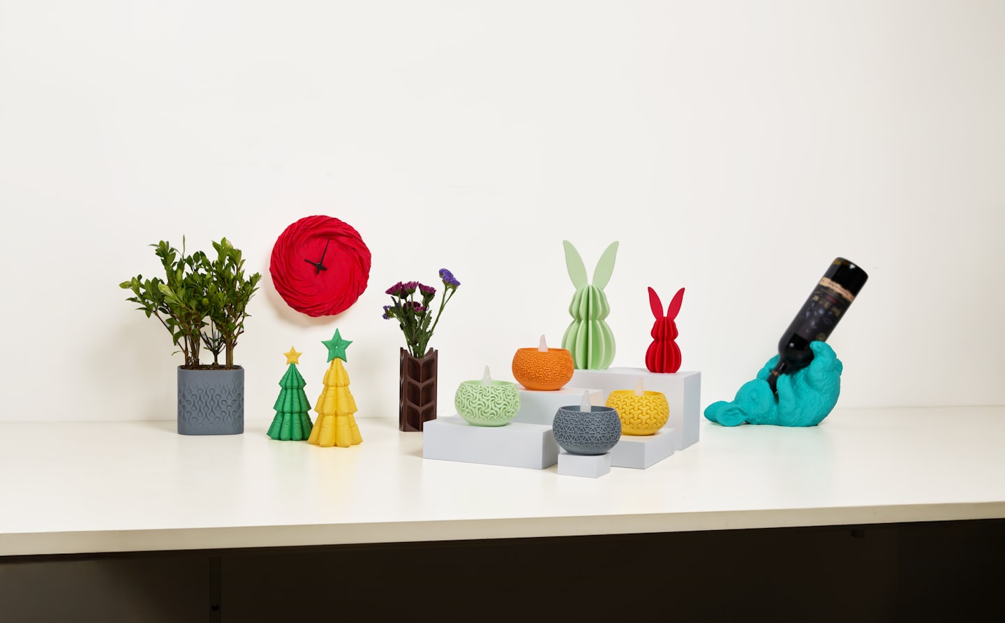 Colorful 3D printed objects and plants on a white table.