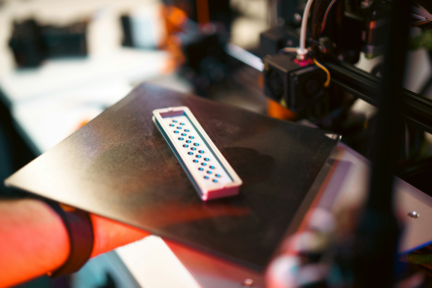 3D printer producing a white object with blue indentations.