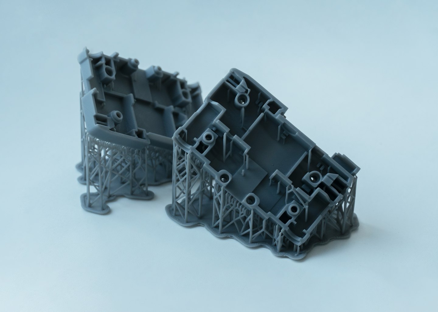 Two gray 3D printed resin prototypes with supports attached.